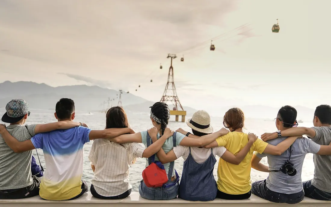 A group of people sitting together with arms around each other, looking out at the horizon